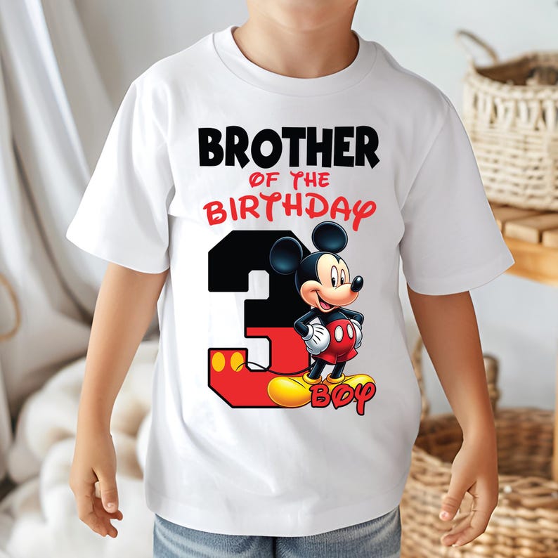 May include: White t-shirt featuring Mickey Mouse and the text "BROTHER OF THE BIRTHDAY 3 BOY". The number 3 is black and red, with Mickey Mouse standing on the number. The shirt is designed for a birthday celebration.