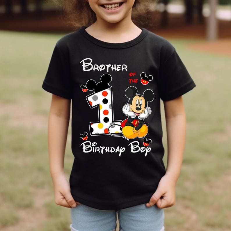 Puede incluir: Camiseta negra de manga corta con el texto "Brother of the 1st Birthday Boy" y un gr&aacute;fico de Mickey Mouse. El n&uacute;mero 1 est&aacute; decorado con lunares. La camiseta est&aacute; dise&ntilde;ada para el cumplea&ntilde;os de un ni&ntilde;o.