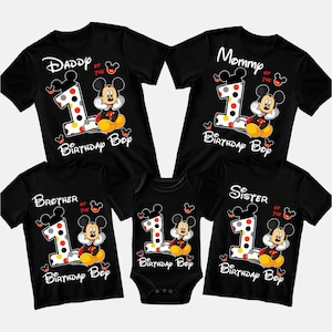 May include: Black family birthday shirts with Mickey Mouse graphics. The shirts say "Daddy", "Mommy", "Brother", and "Sister" with a number 1 and "Birthday Boy" text. A black onesie is also included.