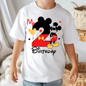 May include: White t-shirt featuring a colorful Mickey Mouse design for a second birthday. The design includes a large number 2, Mickey Mouse in sunglasses, the words "My Birthday", and star and balloon accents. A fun and festive shirt.