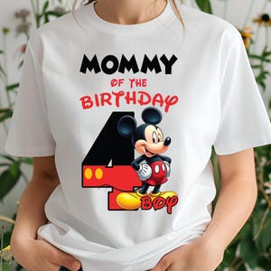 May include: White t-shirt with the text "MOMMY OF THE BIRTHDAY" in black and red. A cartoon Mickey Mouse graphic is featured next to a large number 4. The word "BOY" is written in yellow below Mickey Mouse.