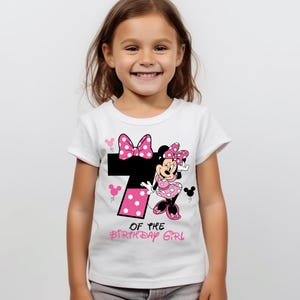 K&ouml;nnte beinhalten: Wei&szlig;es T-Shirt mit einem Minnie Mouse-Design. Das Design umfasst eine gro&szlig;e schwarze Zahl 7 mit rosa Punkten, eine rosa Schleife und den Text "OF THE BIRTHDAY GIRL". Das T-Shirt ist f&uuml;r ein Kind.