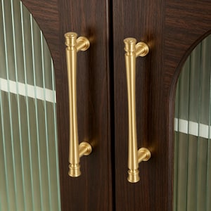 May include: Close-up of a dark brown wooden cabinet door with two long, gold-colored handles. The cabinet door has a glass panel with vertical lines. The handles are vertically oriented and have a decorative design.