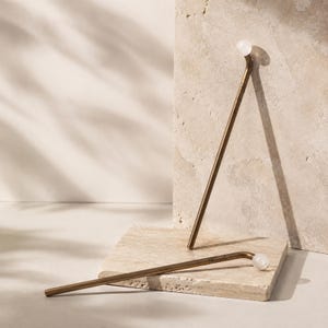 May include: Two L-shaped metal stirring sticks with a matte bronze finish and a small, translucent white spherical bead at the end of each handle. The word "Nicole" is engraved in a cursive script on the side of each metal stirring stick.