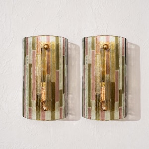 Peut inclure: Une paire d'appliques murales semi-cylindriques présentant un motif en mosaïque verticale de bandes de verre texturé dans des tons rose pâle, vert olive et or clair. Chaque luminaire est fixé par deux petites attaches sphériques en laiton.
