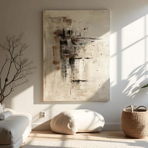 May include: Large abstract painting with beige, brown, and black brushstrokes. The artwork hangs on a white wall, complemented by a neutral-toned interior with a beige ottoman, a woven basket, and a sofa.