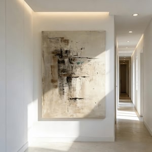 May include: Large abstract painting with beige, brown, and black brushstrokes. The artwork hangs on a white wall in a well-lit hallway. The painting's composition features a mix of geometric and organic shapes.