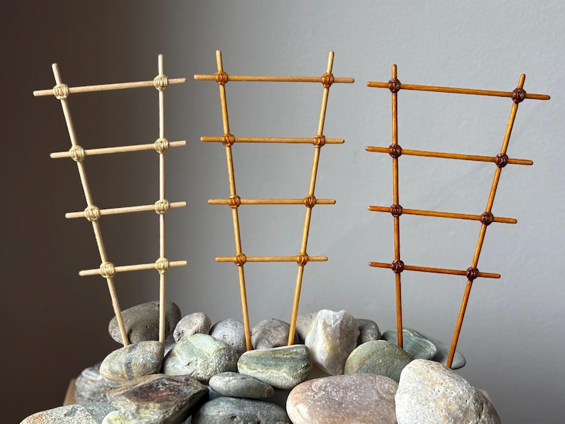 May include: Three ladder-style plant trellises in varying shades of light, medium, and dark brown. Each trellis features four horizontal rungs secured to two vertical supports with knotted cord, creating a tapered, narrow rectangular structure.