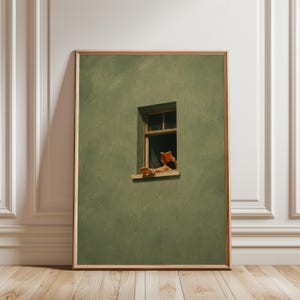 Könnte beinhalten: Ein gerahmter Wandkunstdruck, der eine texturierte olivgrüne Wand mit einem einzelnen rechteckigen Fenster zeigt. Im Fensterrahmen sind ein Paar Füße und Hände zu sehen, wobei die Hände ein offenes orangefarbenes Buch halten.