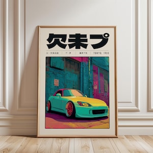 Op de afbeelding: Een ingelijste kunstdruk met een turquoise en gele sportwagen voor een gebouw met turquoise en roze muren. De print bevat Japanse tekst en de woorden "TOKYO, 1923". Het kunstwerk wordt gepresenteerd op een houten vloer.