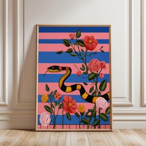 Op de afbeelding: Een ingelijste kunstdruk met een gestileerde slang met zwart-gele strepen, te midden van rode en roze bloemen. De achtergrond heeft horizontale blauwe en roze strepen. Het kunstwerk zit in een gouden lijst.