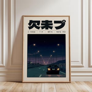 May include: A framed art print depicting a car driving on a highway at night. The print features Japanese text at the top and the words "TOKYO, 1923". The colour scheme includes dark blues, purples, and beige.