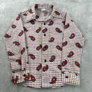 May include: A long-sleeve button-down shirt featuring a white base with a grid pattern of thin black and red lines. The shirt is decorated with a repeating red and black paisley print throughout the fabric, including a pointed collar and cuffs.