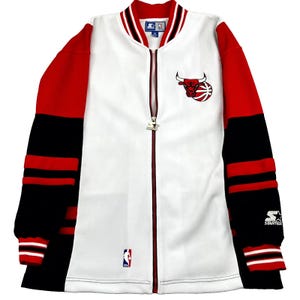 May include: White, red, and black Chicago Bulls zip-up jacket. The jacket features the Bulls logo on the chest, red sleeves with black and red stripes, and a Starter logo. The NBA logo is also visible.