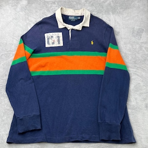 May include: Navy blue long-sleeve rugby shirt with orange and green stripes across the chest and sleeves. Features a white collar and the text "CLASS 61" on the chest. A small yellow logo is on the right chest.