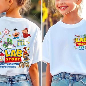 May include: White t-shirts with science-themed graphics. One shirt features a "Lab Week 2026" design on the front. The other shirt has a "Lab Story" design with lab equipment and the text "To infinity and beyond for our patients."