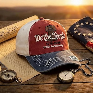 May include: A red, white, and blue baseball cap with the text "We the People" and "1776-2026 250th Anniversary." The cap has a distressed denim brim and a small patch that reads "Defend Liberty."