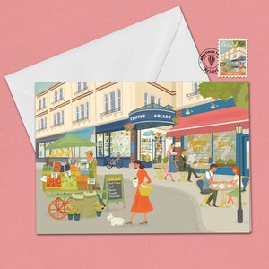 Peut inclure: Une illustration colorée d'une scène de rue à Bristol, en Angleterre. L'illustration présente un stand de fruits, un café et des gens qui marchent dans la rue. Le texte "Clifton Arcade" est visible au-dessus du café.