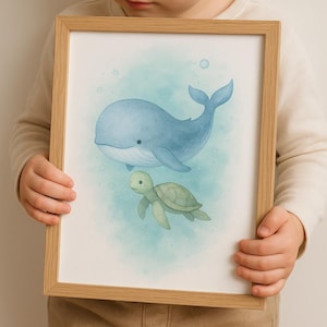 Könnte beinhalten: Ein gerahmter Aquarelldruck mit einem blauen Wal und einer grünen Meeresschildkröte, die in einem türkisfarbenen Ozean schwimmen. Das Kunstwerk befindet sich in einem hellbraunen Holzrahmen, ideal für ein Kinderzimmer.