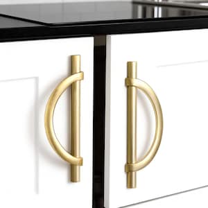 May include: Close-up of two white cabinet doors with gold-colored, semi-circular handles. The handles are mounted vertically and have a cylindrical bar on each end. The cabinet doors are set against a black countertop and white tile background.