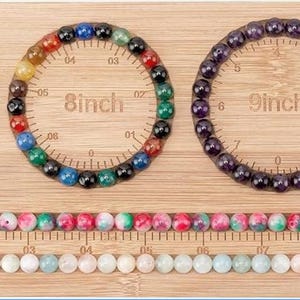 May include: A bamboo bead design board featuring three circular channels labeled 7inch, 8inch, and 9inch, each containing a beaded bracelet. The board includes a rectangular compartment with loose beads and two long horizontal channels filled with beads.