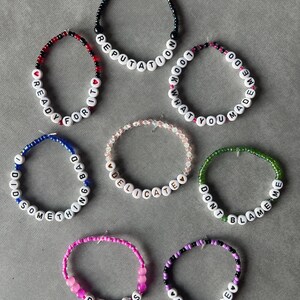 May include: Seven beaded bracelets featuring white letter beads spelling out REPUTATION, READY FOR IT, LOOK WHAT YOU MADE ME DO, I DID SOMETHING BAD, DELICATE, DONT BLAME ME, DRESS, and END GAME, accented with various colored beads and small heart shapes.