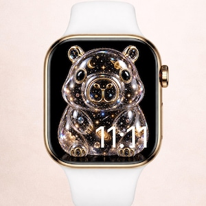 Könnte beinhalten: Eine Smartwatch mit einem goldfarbenen rechteckigen Gehäuse und einem weißen Silikonarmband. Das digitale Display zeigt eine durchscheinende, kristalline Bärenfigur, gefüllt mit einem galaktischen Muster aus Sternen, Planeten und dem Text 11:11.
