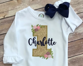 Floral 1st birthday design on a White Ruffled long Sleeve Romper.