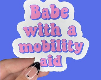 May include: White sticker with the text "Babe with a mobility aid" in pink letters with a blue outline.