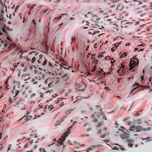 Puede incluir: Un rollo de tela transparente con un patrón de estampado animal repetitivo en tonos rosa, blanco y negro. El material ligero está drapeado en pliegues suaves, mostrando la calidad translúcida del tejido y las manchas de leopardo detalladas.