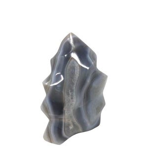 Peut inclure: Une sculpture en pierre d'agate polie. La pierre présente des bandes de couleurs grises, blanches et translucides. La sculpture a un sommet pointu et une forme organique texturée, idéale pour la décoration intérieure ou comme cadeau unique.