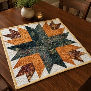 Puede incluir: Un tapete de mesa cuadrado acolchado con un patrón de estrella central en tonos azul verdoso oscuro, naranja quemado y marrón. El diseño incluye costuras complejas en toda la tela, terminado con un borde de color amarillo claro.