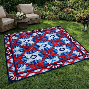 Puede incluir: Un edredón rectangular con un diseño patriótico, con patrones geométricos rojos, blancos y azules. El edredón está colocado sobre un césped verde, mostrando un borde detallado y elementos de diseño centrales. Las dimensiones del edredón no son visibles.