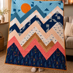Puede incluir: Una colcha rectangular con un diseño de paisaje montañoso y un sol naranja brillante. El patrón consta de bandas en zigzag superpuestas en tonos azul marino, coral, tostado y crema, decoradas con pequeños motivos estampados de ciervos y pinos.