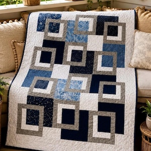 May include: A quilt featuring a geometric pattern of interlocking squares in shades of navy blue, light blue, grey, and white. The fabric displays various textures and subtle prints, with a consistent white background and a dark blue border.