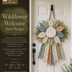 以下が含まれることがあります： Wildflower WelcomeドアハンガーのデジタルPDFパターン。セージ、ダスティブルー、クリーム色の花柄の3層キルト生地で作られた花で、中央は渦巻き状のキルティングが施されています。サイズは幅36cm、高さ51cmです。