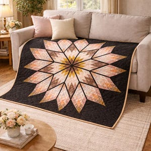May include: A black quilt with a large, geometric starburst design in shades of peach, brown, and gold. The quilt is draped over a beige sofa, creating a cozy and inviting atmosphere. The quilt is approximately 60 inches by 70 inches.