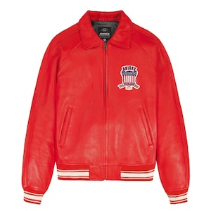 May include: A bright red leather jacket featuring a front zipper closure, a classic collar, and ribbed cuffs and hem with white stripes. On the left chest, there is an embroidered patch displaying the text AVIREX above a shield with stars and stripes.