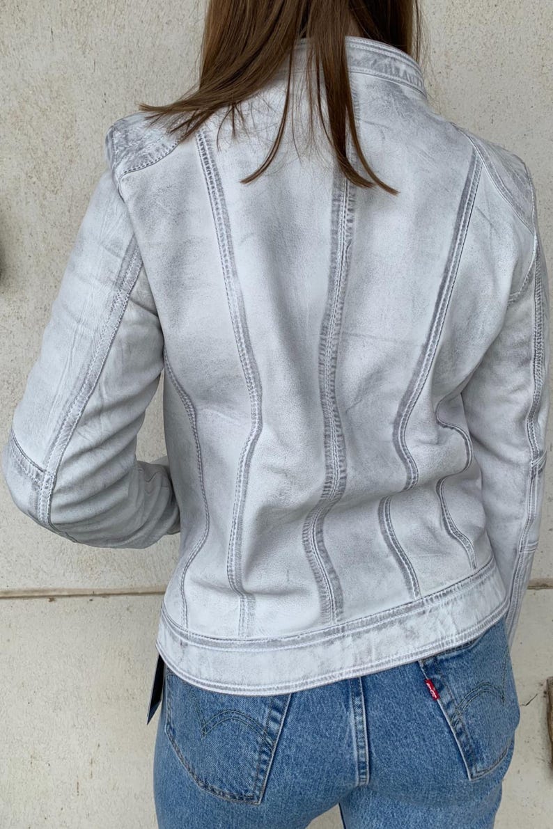 K&ouml;nnte beinhalten: Hellgraue Jeansjacke mit sichtbaren N&auml;hten. Die Jacke hat ein klassisches Design mit Kragen, Kn&ouml;pfen und Taschen. Das Model tr&auml;gt blaue Jeans. Die Jacke scheint aus strapazierf&auml;higem Denim-Material zu sein.
