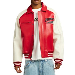 May include: A red and off-white varsity jacket featuring a pointed collar, a front zipper closure with snap buttons, and ribbed cuffs with red and white stripes. The chest displays an embroidered Avirex logo with a wing graphic detail.