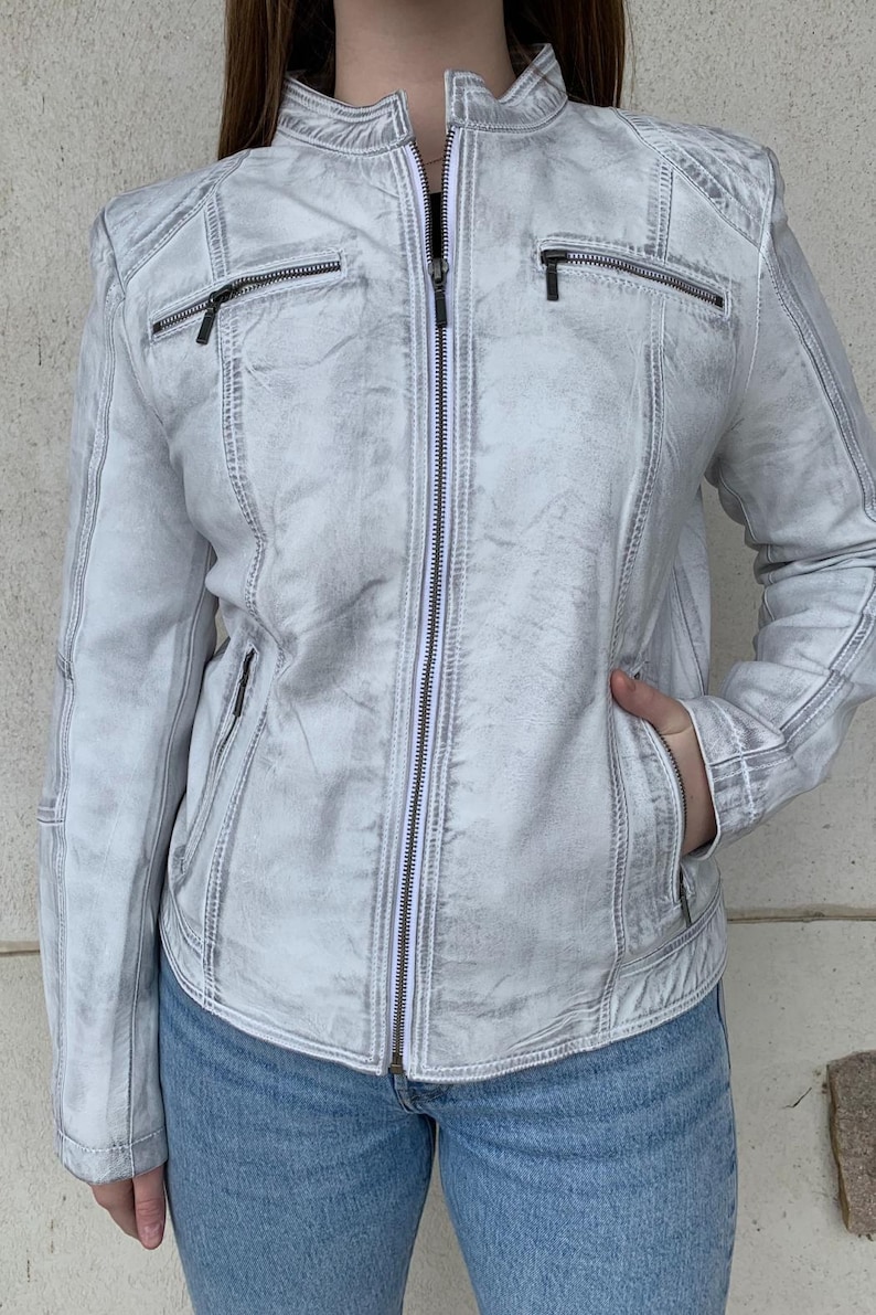 K&ouml;nnte beinhalten: Hellgraue Jacke mit Rei&szlig;verschluss und Used-Look. Die Jacke hat einen Stehkragen, mehrere Rei&szlig;verschlusstaschen und gesteppte Schulterdetails. Das Model tr&auml;gt eine blaue Jeans. Die Jacke ist eine stilvolle Oberbekleidung.