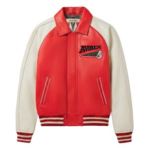 May include: A red and off-white varsity jacket featuring a classic collar, long sleeves, and a front button closure. The chest displays an embroidered Avirex logo with a graphic of a profile head. The cuffs and hem have red and white stripes.