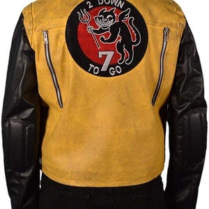 Könnte beinhalten: Senfgelbe Lederjacke mit schwarzen Ärmeln und einem schwarzen Aufnäher auf dem Rücken. Der Aufnäher zeigt eine Cartoon-Katze mit einem Dreizack und dem Text "2 DOWN 7 TO GO" in einem kreisförmigen Design.