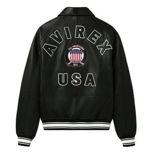 May include: A black leather jacket featuring a white embroidered AVIREX logo in an arc across the upper back. Below the logo is a circular patch with a flag design and the text ALL AMERICANS ESTABLISHED 1975. The word USA is printed below.