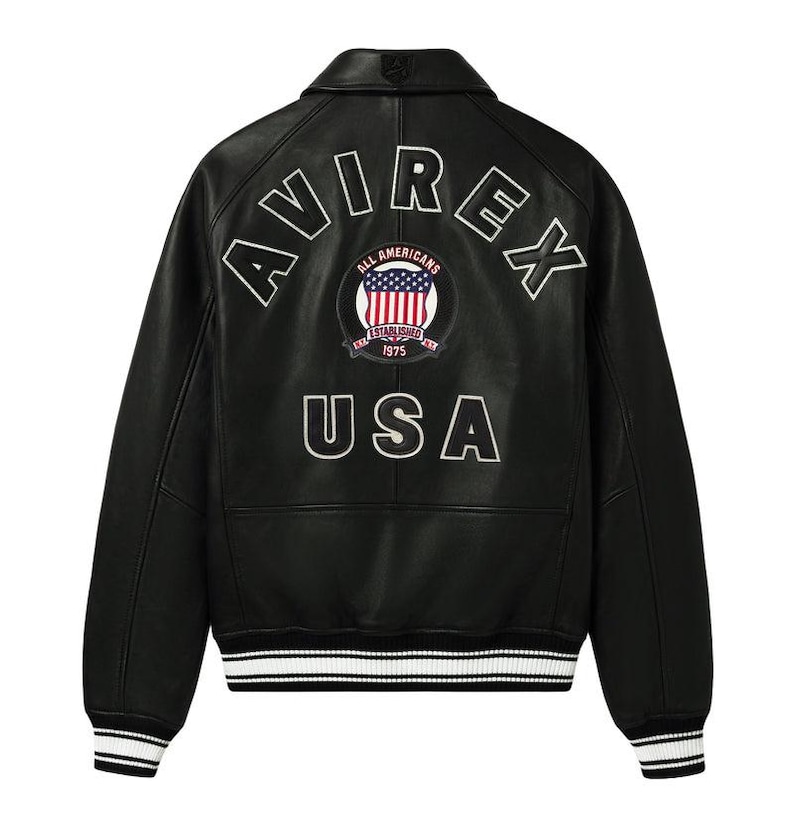 May include: A black leather jacket featuring a white embroidered AVIREX logo in an arc across the upper back. Below the logo is a circular patch with a flag design and the text ALL AMERICANS ESTABLISHED 1975. The word USA is printed below.
