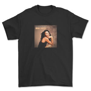 May include: Black t-shirt featuring a square image of Olivia Dean. The image shows Dean in a black dress, with the text "OLIVIA DEAN MAN I NEED" above her. The shirt is made of a soft, comfortable material.