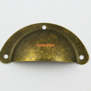 May include: A brass cabinet knob with a rounded, slightly domed shape. The knob has three holes for mounting and a distressed finish.