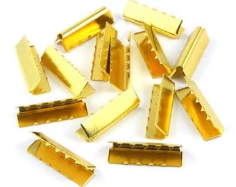 May include: A group of 14 gold metal slider buckles. The buckles are rectangular with a serrated edge and a small hole at each end.