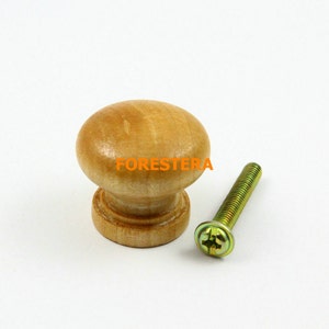 Op de afbeelding: Een houten knop met een ronde bovenkant en een platte onderkant. De knop is lichtbruin van kleur en wordt geleverd met een schroef.