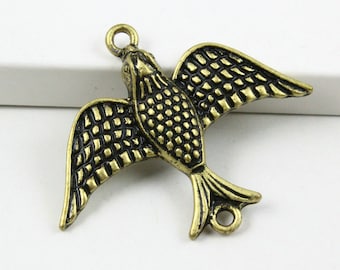 Könnte beinhalten: Ein goldfarbener Vogel-Anhänger aus Metall mit einem detaillierten, strukturierten Design. Der Vogel hat ausgebreitete Flügel und eine kleine Schlaufe oben zum Anbringen an Schmuck oder Bastelarbeiten.